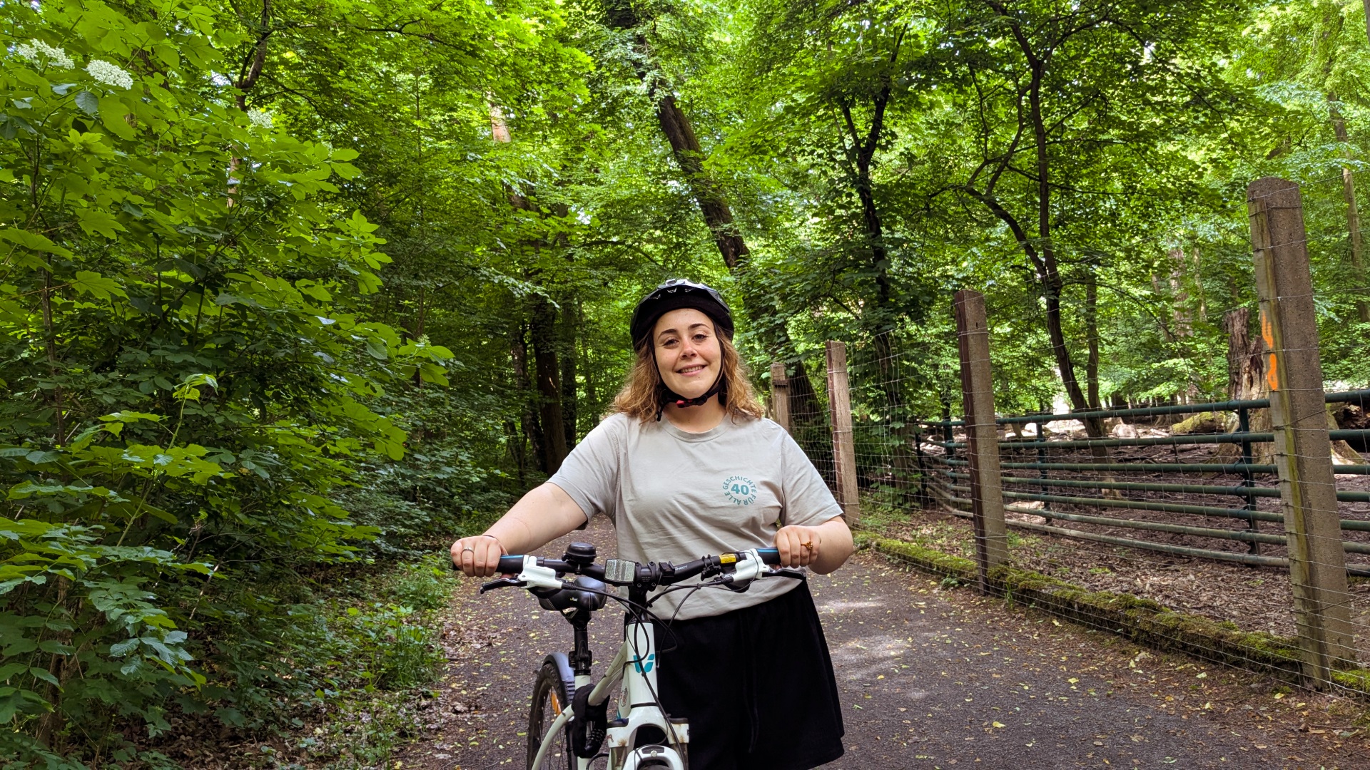 Mitarbeiterin Almudena Serrano steht neben ihrem Fahrrad im Park