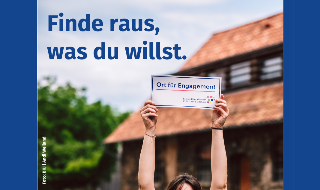 Fotografie mit einem unscharfem Gebäude im Hintergrund. Die Schrift "Finde raus, was du willst" ist über den Himmel im linken Bildrand gelegt. Im Vordergrund sind zwei Arme sichtbar die ein Schild hochhalten. Auf dem Schild steht "Ort für Engagement Freiwilligendienste Kultur und Bildung"." 