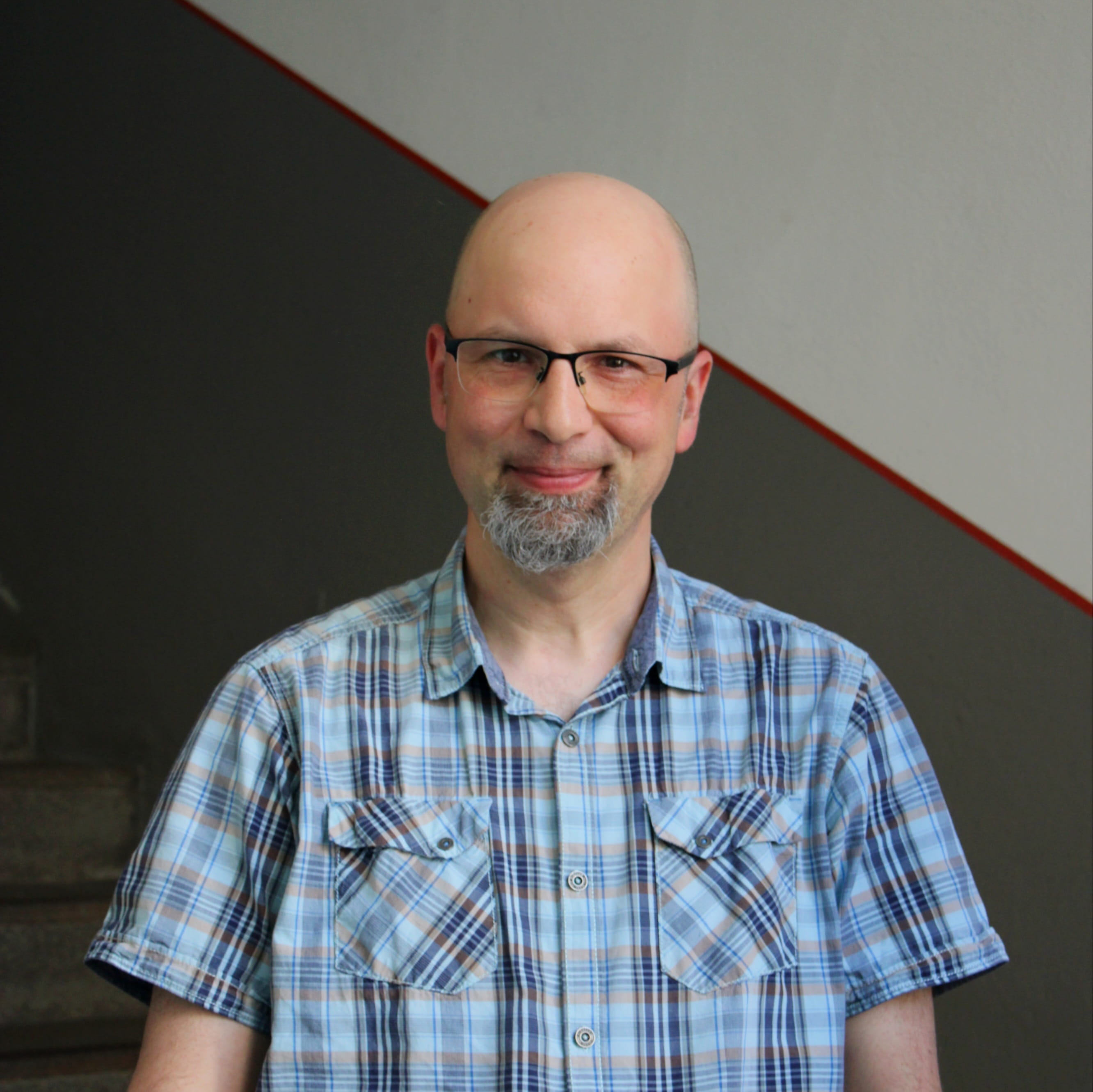 Alexander Estel ist Mitarbeiter für Geschichte Für Alle e.V. im Bereich Schiffs- und Bustouren Nürnberg. Er trägt ein kariertes Hemd und blickt lächelnd in die Kamera.