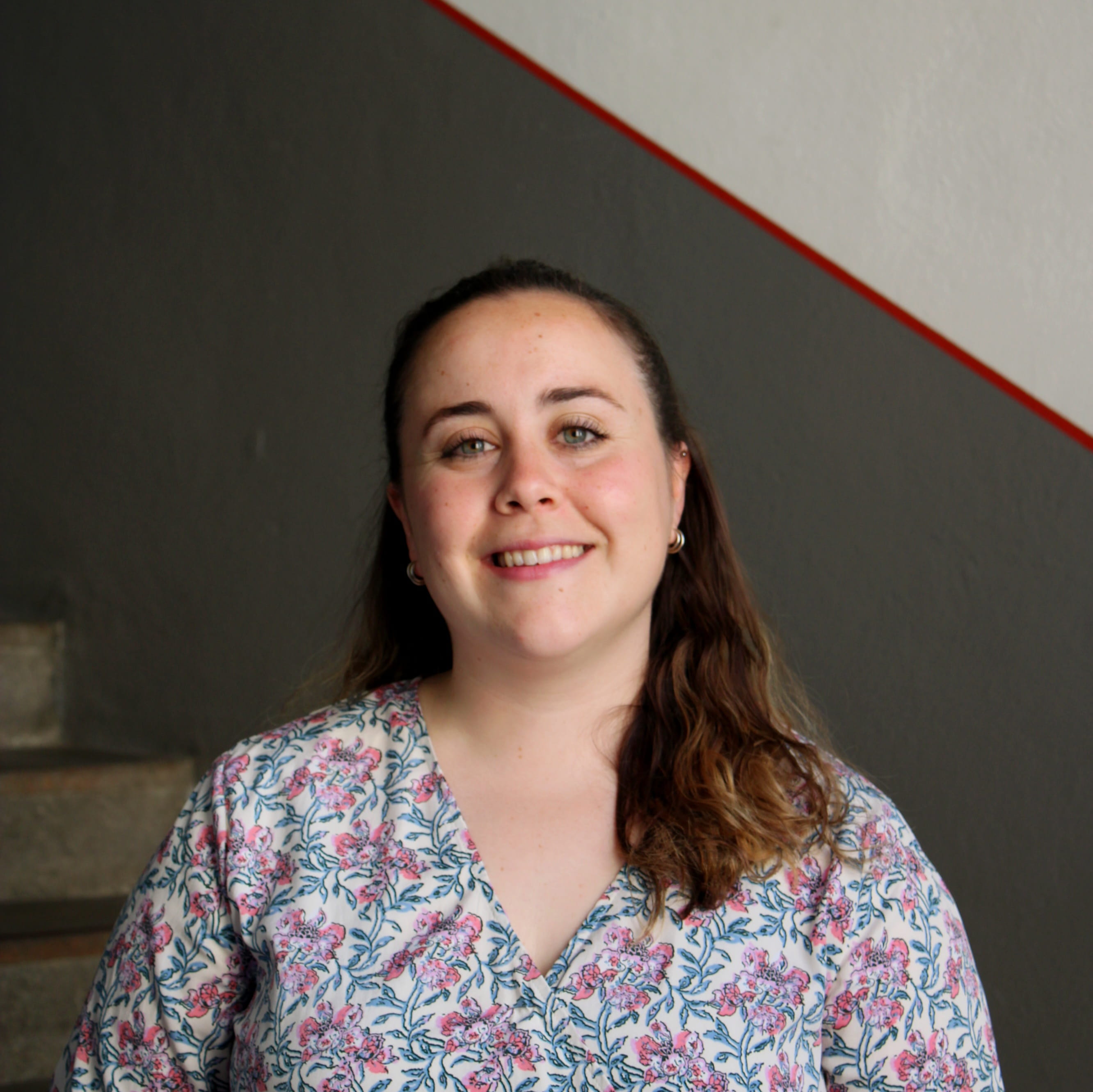 Almudena Serrano arbeitet im Buchungsbüro in Nürnberg. Sie trägt eine helle Bluse und lächelt in die Kamera.