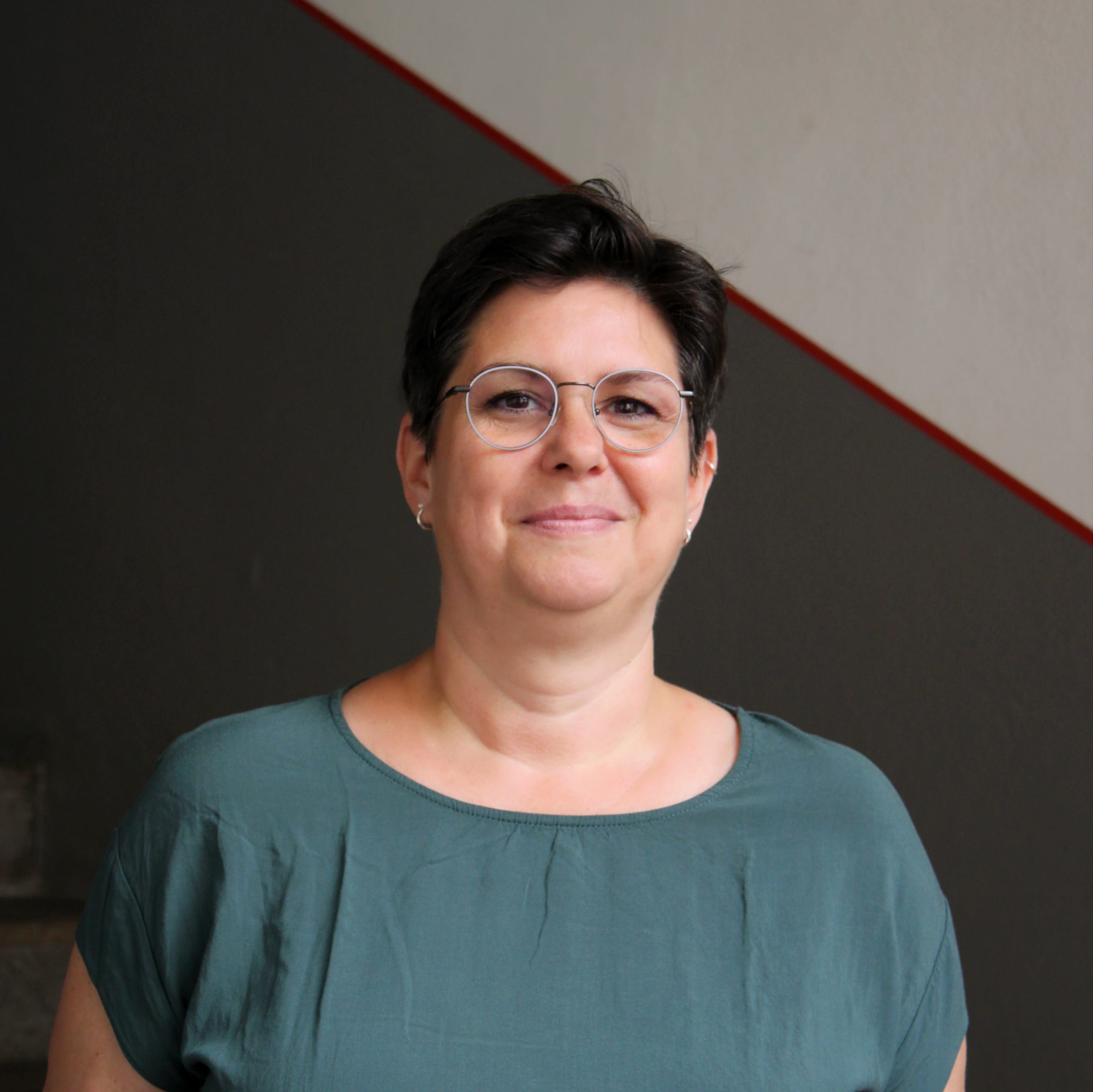 Franca Heinsch ist die Leiterin des Buchungsbüros von Geschichte Für Alle e.V. in Bamberg. Auf dem Bild trägt sie ein blau-grünes Oberteil und blickt lächelnd in die Kamera.