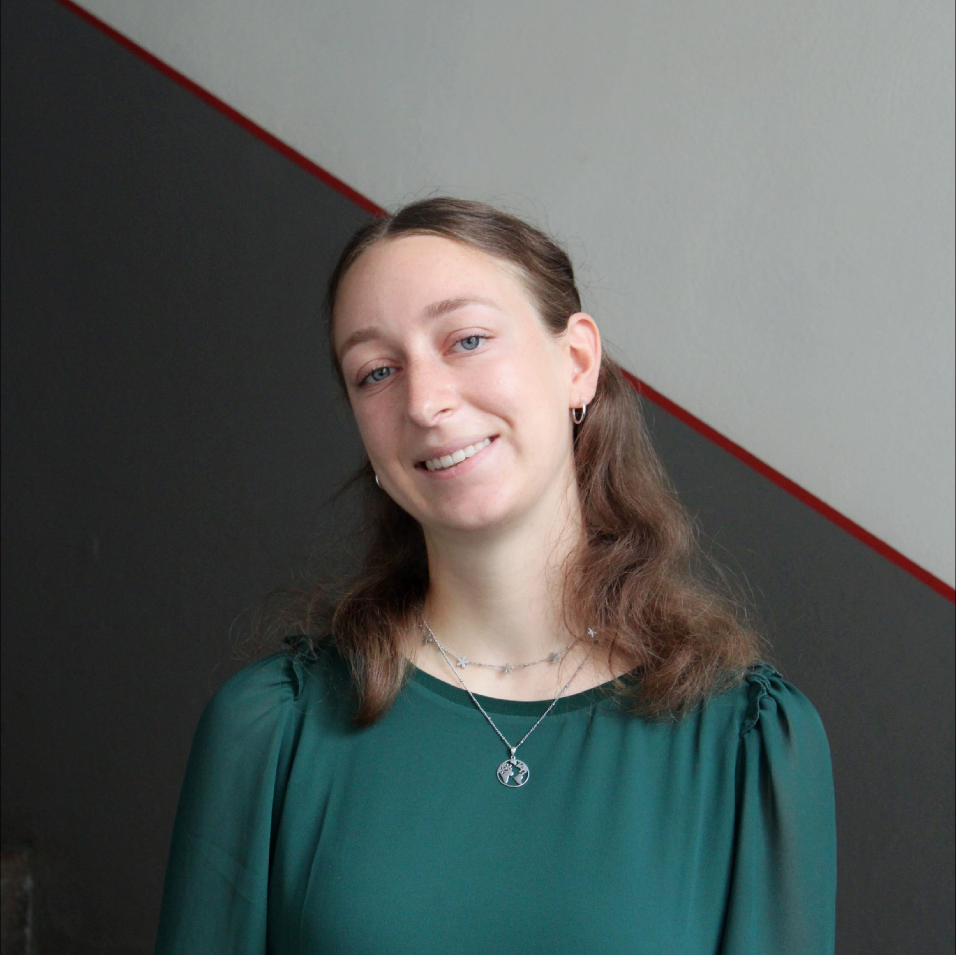 Klara Lauber absolviert ihren Bundesfreiwilligendienst bei Geschichte Für Alle e.V.. Auf dem Foto trägt sie eine grüne Bluse und lächelt in die Kamera.