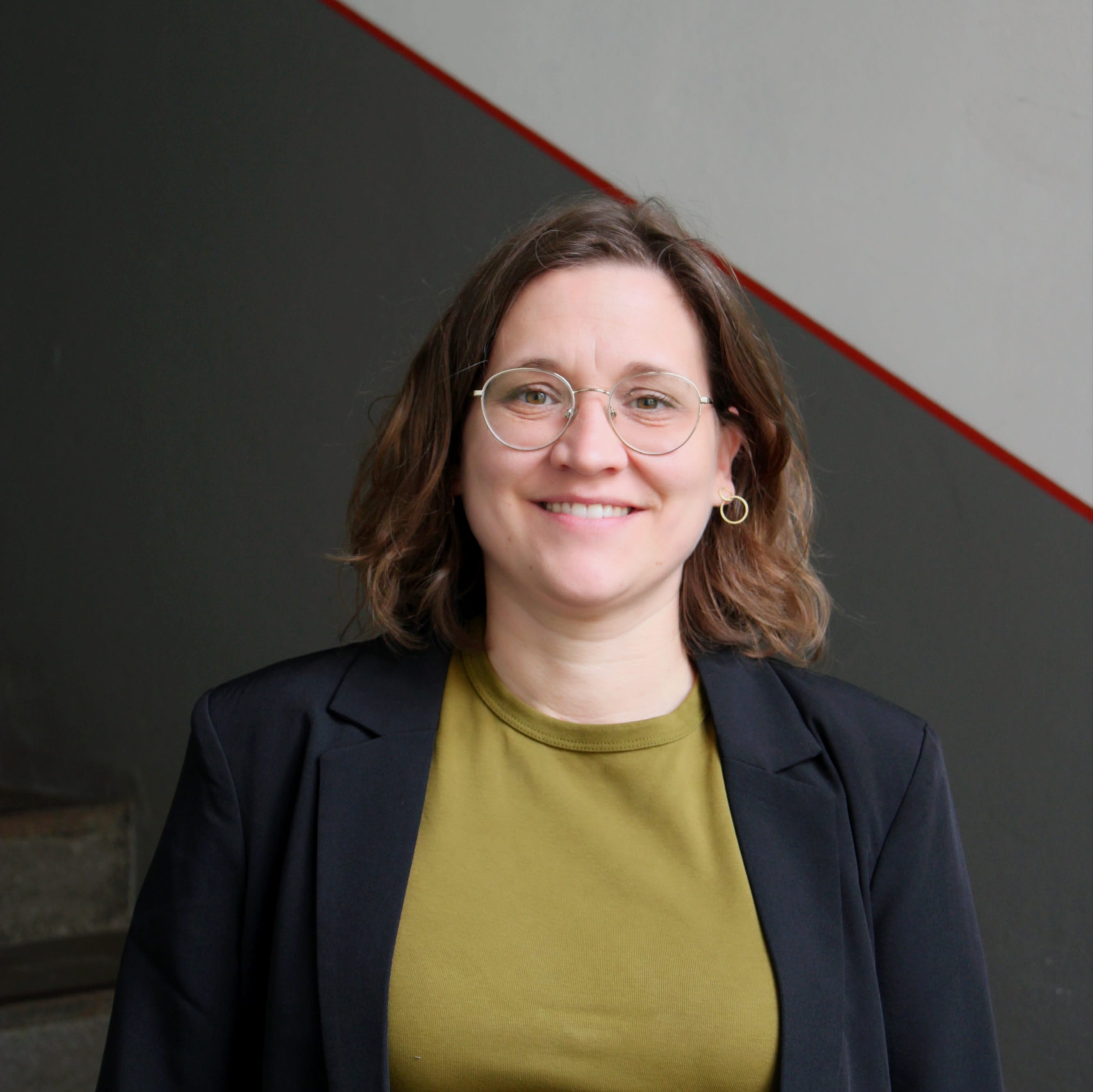 Stefanie Roppelt arbeitet im Bereich Schiffs- und Bustouren in Bamberg. Sie trägt ein grünes Oberteil mit Blazer und lächelt in die Kamera.
