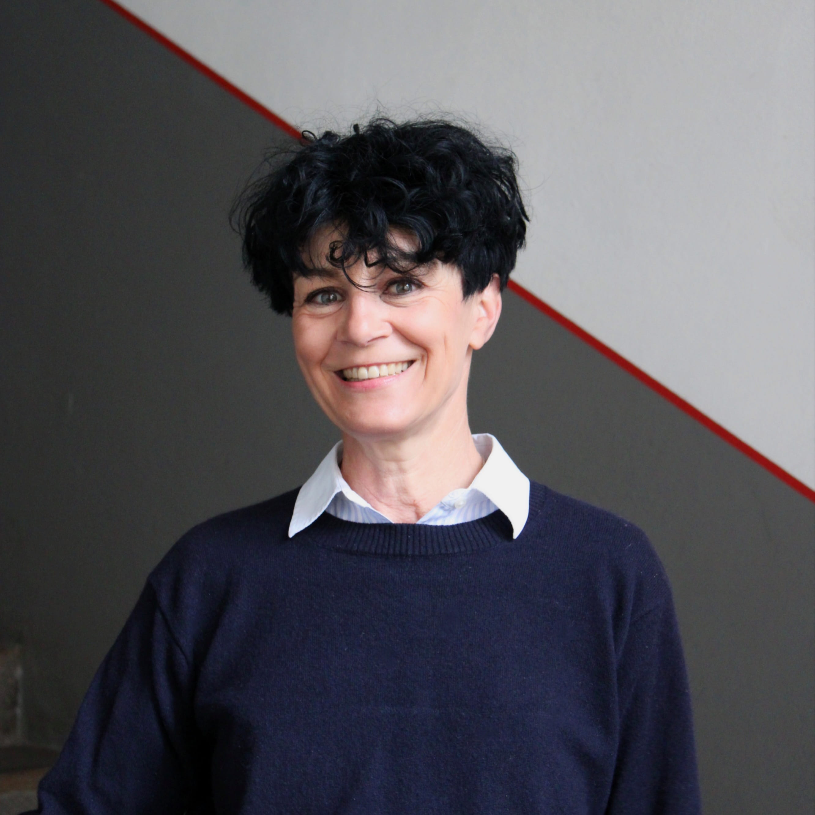 Ulrike Hauffe ist Mitarbeiterin im Henkerhaus Nürnberg. Sie trägt ein dunkles Oberteil und blickt lächelnd in die Kamera.