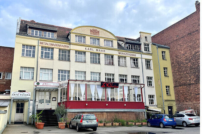 Großes Haus in Gostenhof mit der Aufschrift 'Karl Mahr Metallwarenfabrik', im Erdgeschoss Restaurant mit Wintergarten, davor parkende Autos