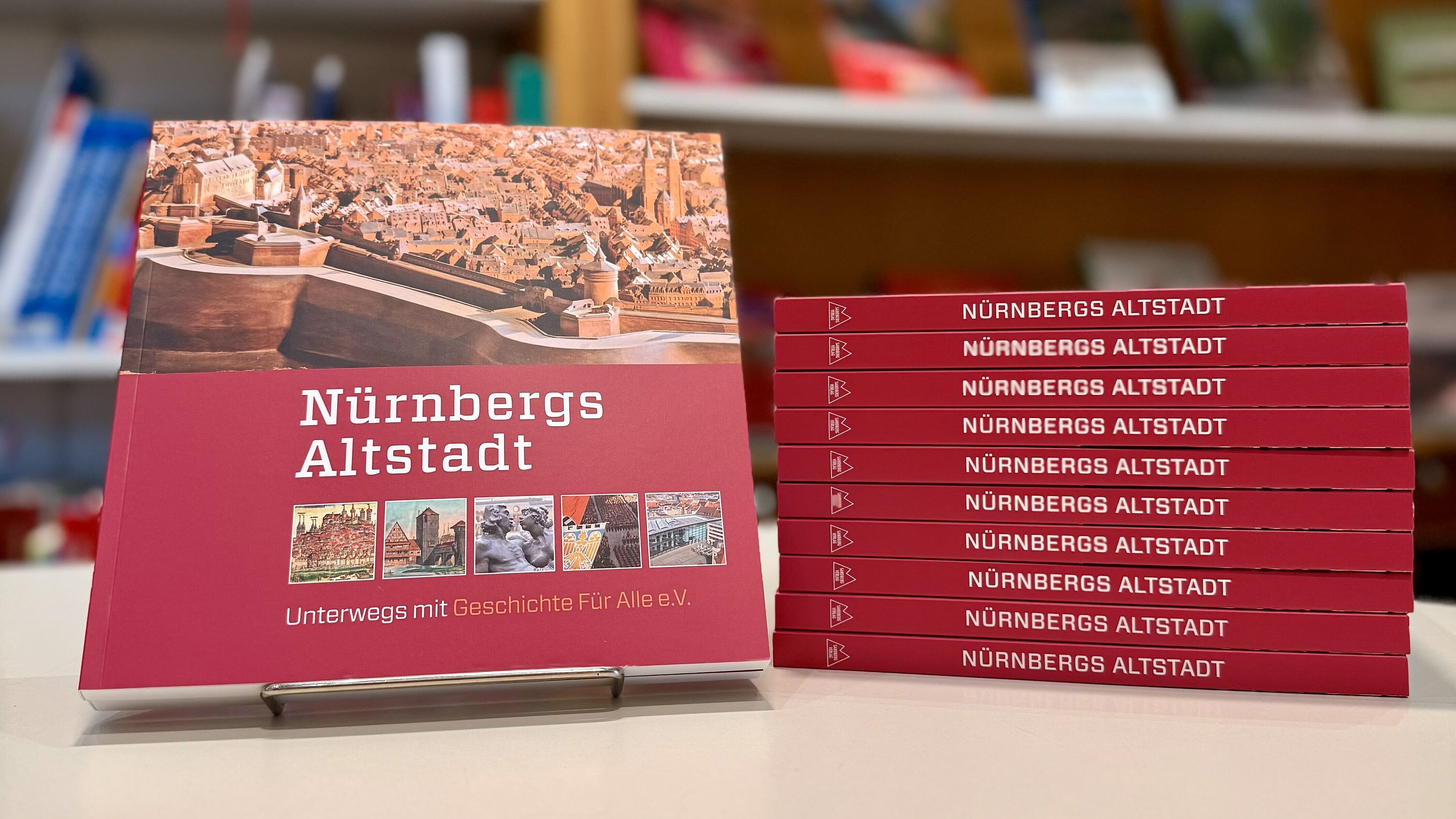 Links ist das quadratische Buch mit rotem Cover "Nürnbergs Altstadt" zu sehen, recht davon sind weitere Exemplare aufgestapelt.