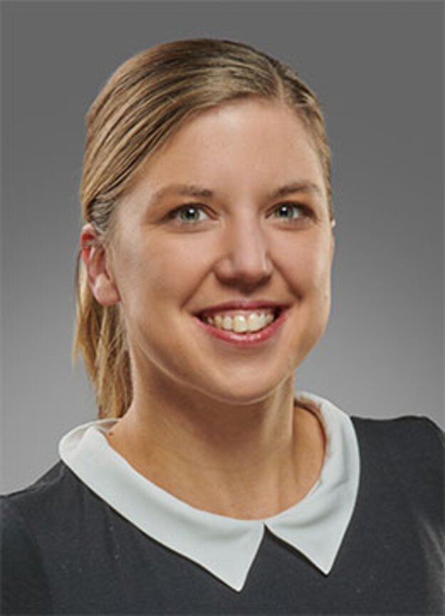 Mitarbeiterin Jennifer Oevermann, lächelnd vor grauem Hintergrund