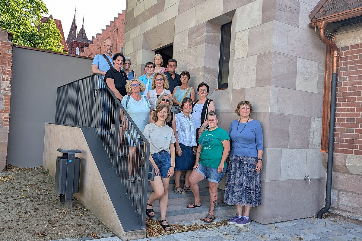 Gruppenbild der ca. 15 Ehrenamtlichen, die den Turm "Blaues G" künftig öffnen werden, auf der Treppe vor dem Turm.