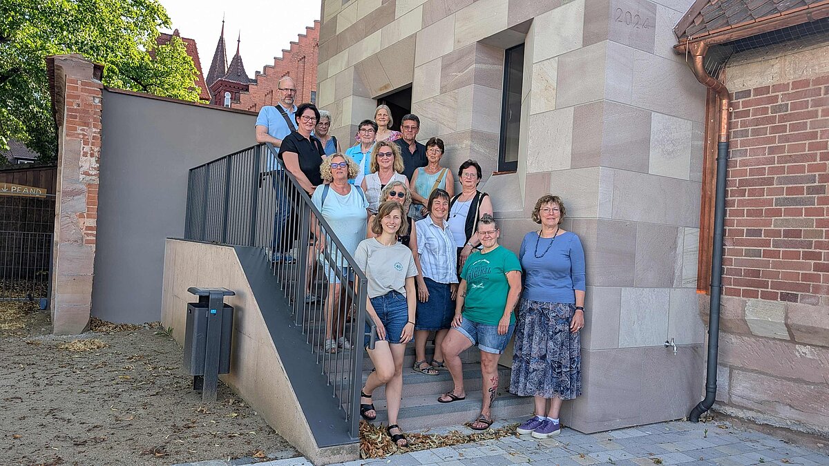 Gruppenbild der ca. 15 Ehrenamtlichen, die den Turm "Blaues G" öffnen werden, auf der Treppe vor dem Turm.