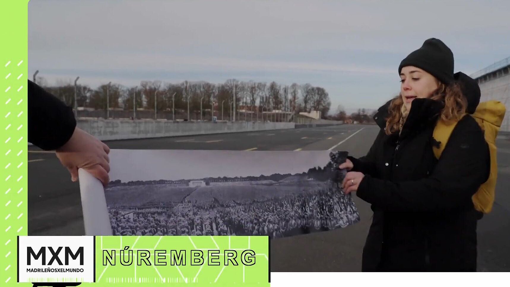 Almudena steht steht im Außenbereich und hält ein großes Panoramabild einer Versammlung von SA und SS auf den Reichsparteitage in die Kamera.
