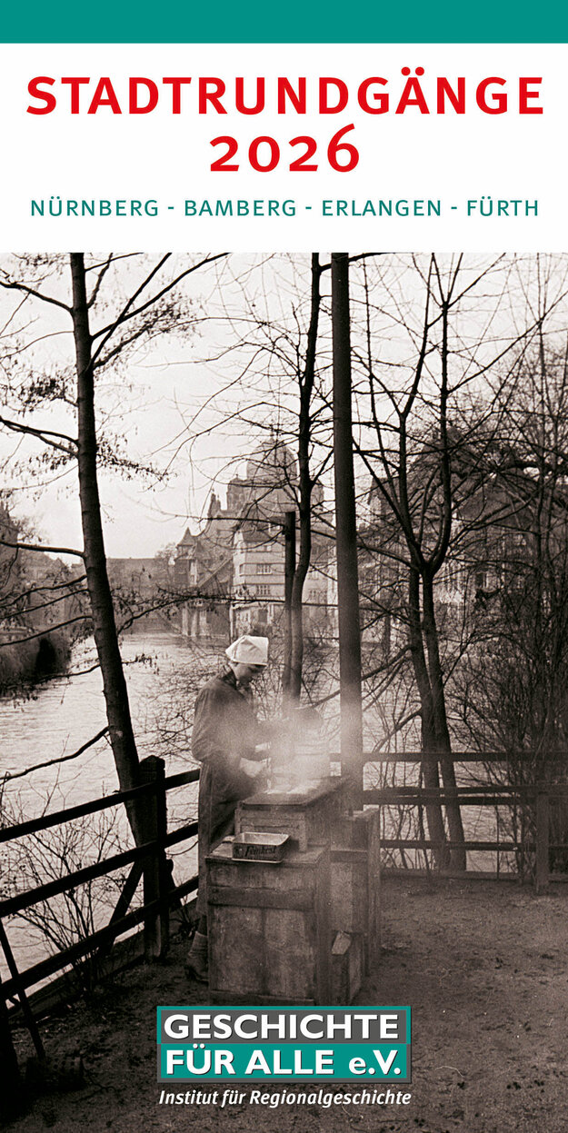 Schwarz-Weiß-Fotografie einer Bratwurstverkäuferin auf der Insel Schütt in Nürnberg im Jahr 1938. Im Hintergrund die Synagoge am Hans-Sachs-Platz, die wenige Monate später abgerissen wurde. Es ist Winter.