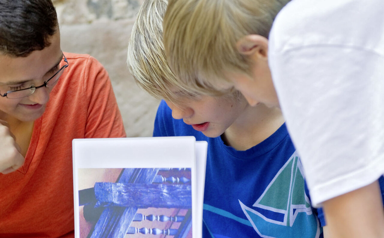 Drei Jungen schauen sich das Bild einer Holzkonstruktion an