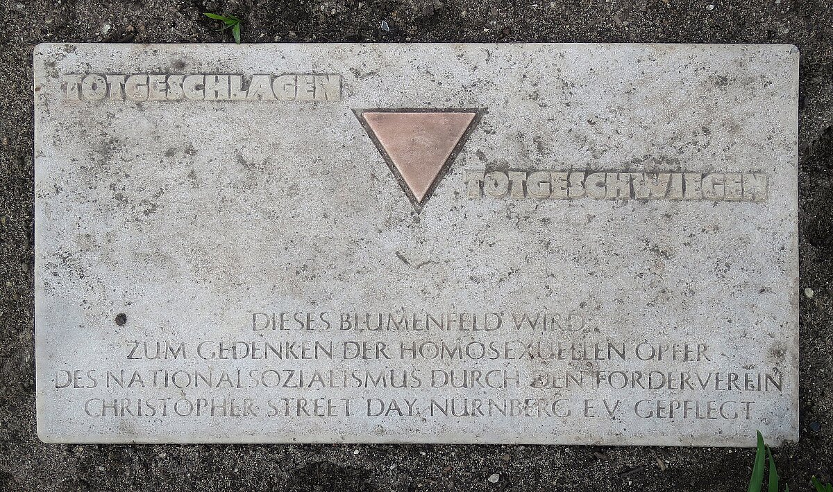 Steintafel am Magnus-Hirschfeld-Platz in Nürnberg mit der Aufschrift "Totgeschlagen, totgeschwiegen. Dieses Blumenfeld wird zum Gedenken der homosexuellen Opfer des Nationalsozialismus durch den Förderverein Christopher Street Day, Nürnberg e.V. gepflegt