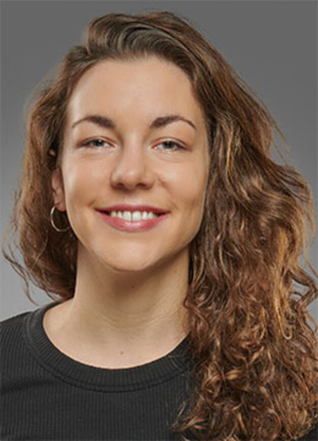 Mitarbeiterin Roxanne Narz, lächelnd vor grauem Hintergrund