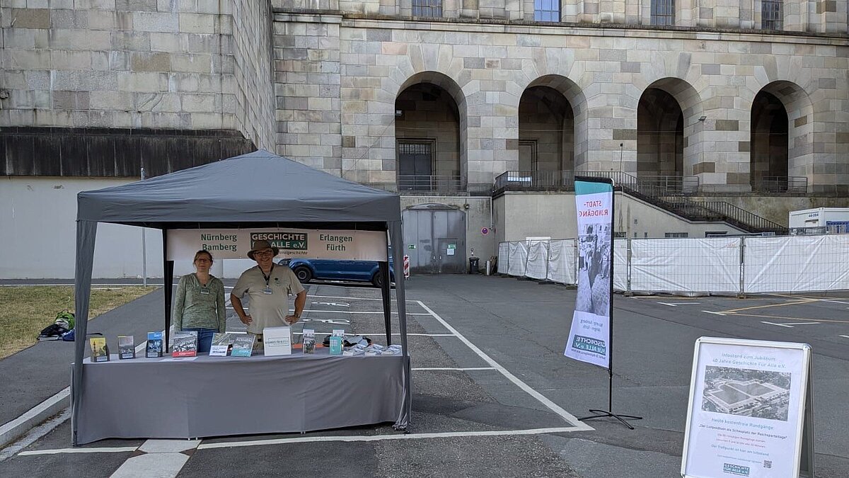 Dagmar Seck und Robert Dietz am Infostand, GFA 2025. Infostand von Geschichte Für Alle mit zwei Personen vor der Kongresshalle