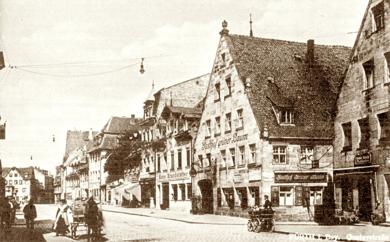 Schwarzweißaufnahme von einer Häuserzeile, davor eine gepflasterte Steinstraße
