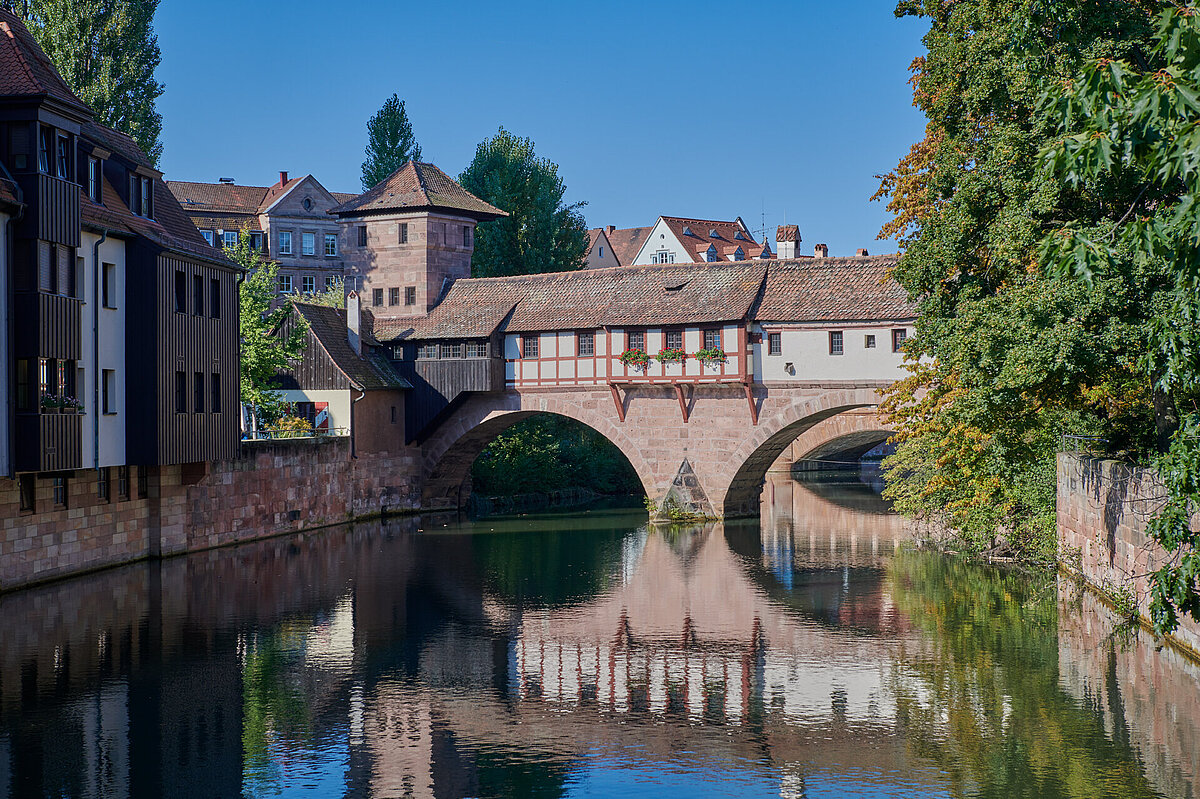 über einen Fluss führt eine Brücke, die mit mittelalterlichen Fachwerkhäusern überbaut ist