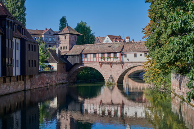 über einen Fluss führt eine Brücke, die mit mittelalterlichen Fachwerkhäusern überbaut ist