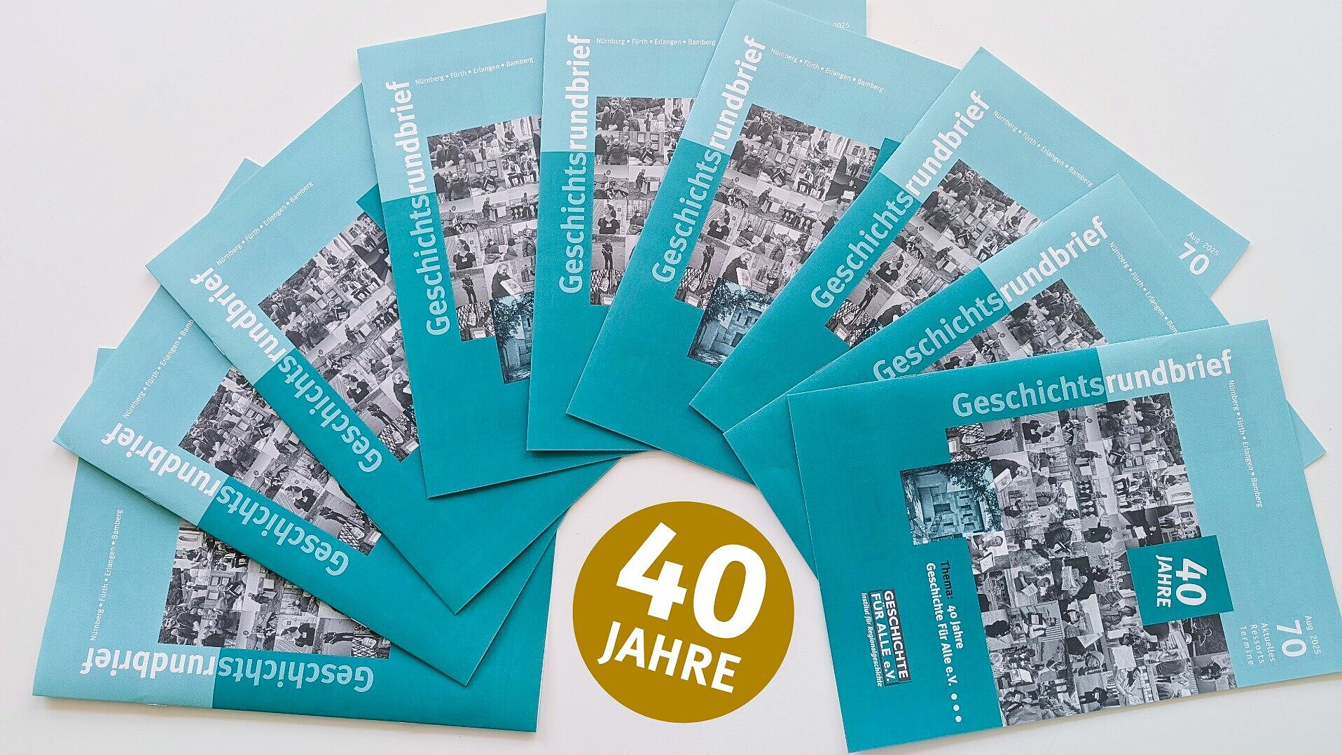Sieben Ausgaben des aktuellen Geschichtsrundbriefs zum 40-jährigen Bestehen des Vereins liegen aufgefächert auf einem weißen Tisch, dazu ein goldener Sticker mit der Aufschrift '40 Jahre'