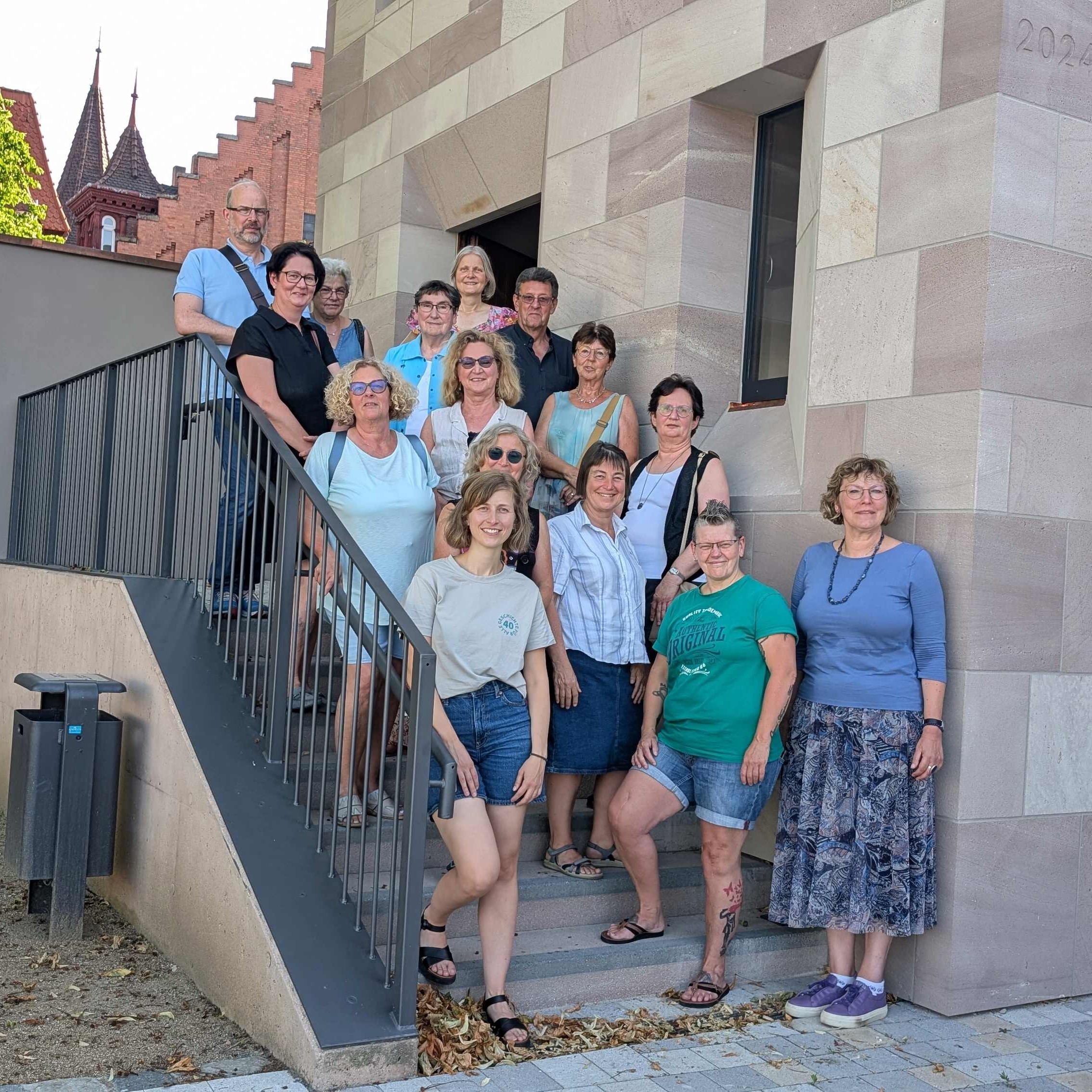 Das Foto zeigt ehrenamtliche Turmwächterinnen und Turmwächter auf einer Treppe vor dem Lernort Stadtmauer.